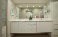 A fresh all-white, contemporary bathroom design by Dan Luck of Bella Domicile featuring Dura Supreme Cabinetry.