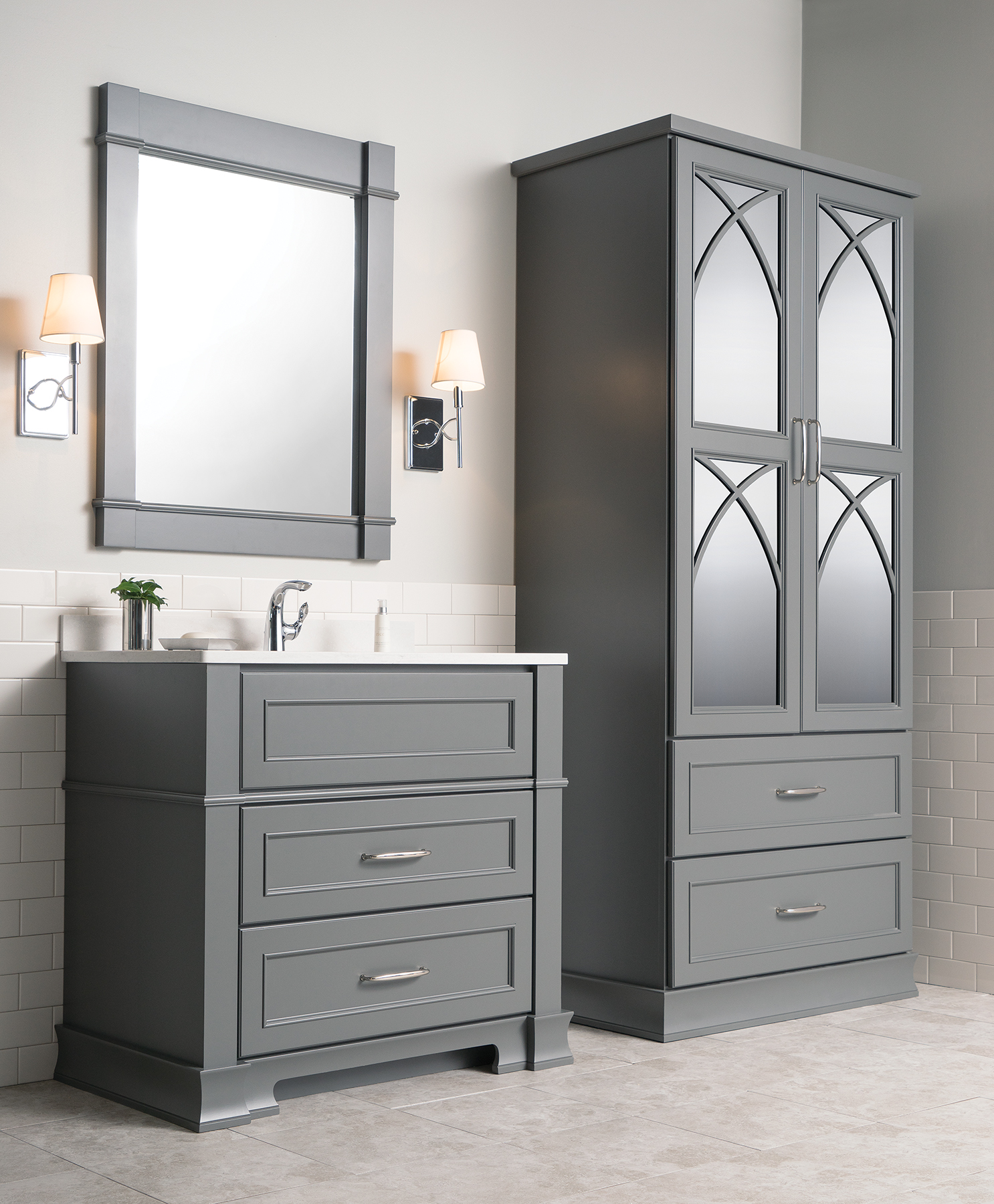 Dark gray bathroom furniture set with a vanity and a free-standing linen cabinet with decorative mirror cabinet doors.