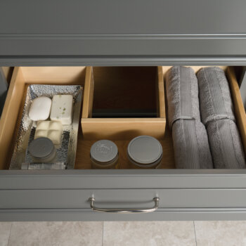A Plumbing Drawer in a vanity cabinet. The drawer shape wraps around the plumbing fixtures under the sink.