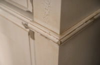A close up of the molding details on the corner of a furniture styled vanity.
