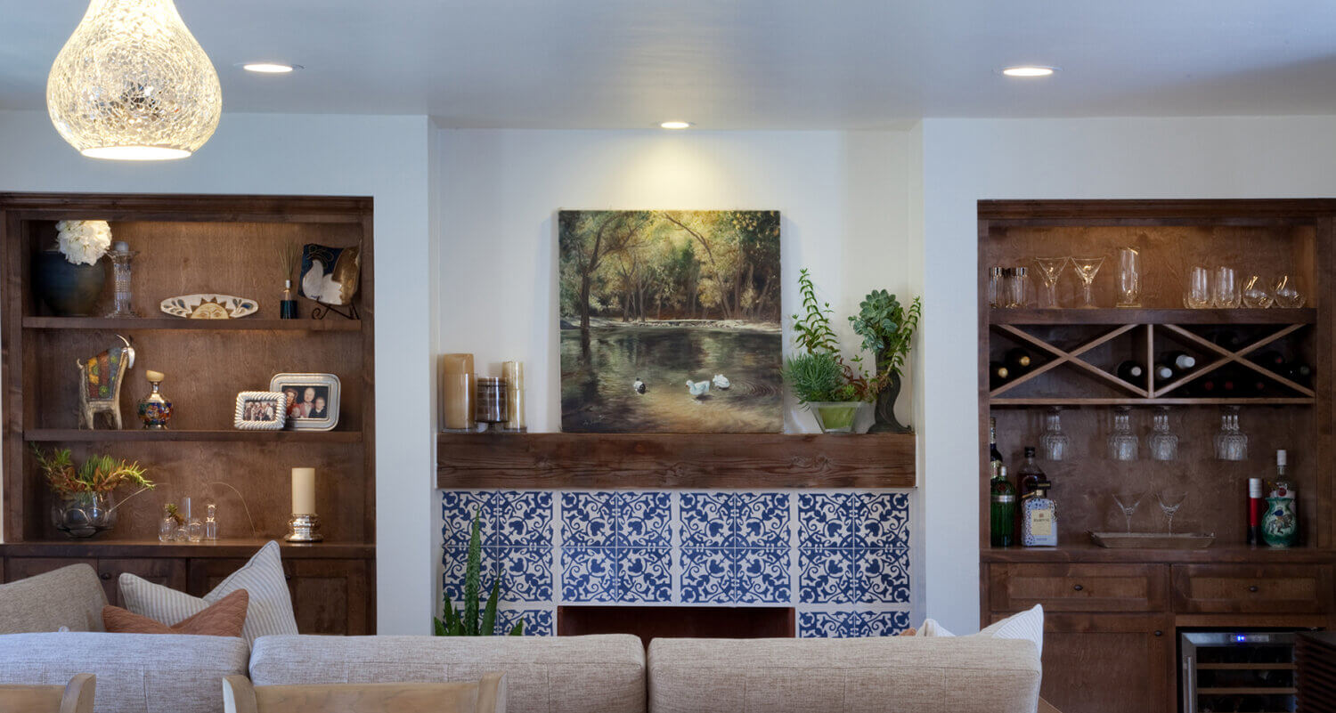 A modern transitional fireplace wall with built-in bookshelves and blue and white hand-painted tiles.