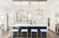 A bright white and navy blue trendy kitchen design with gold and bass hardware & light fixtures.