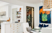 A luxurious kitchen and dining room design with access to a walk-in wine room. The white painted cabinets are bright and beautiful with the gold hardware accents.