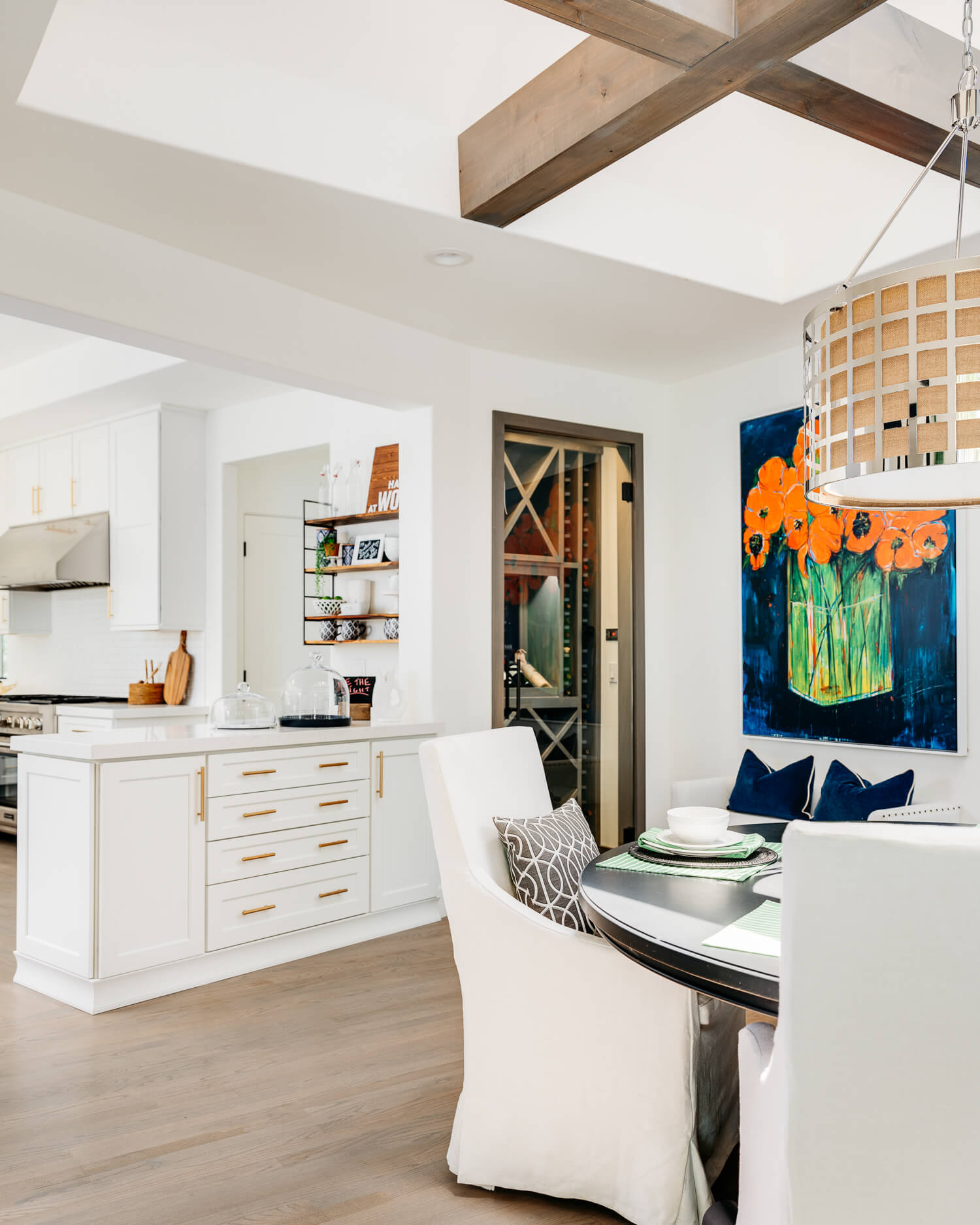 A luxurious kitchen and dining room design with access to a walk-in wine room. The white painted cabinets are bright and beautiful with the gold hardware accents.