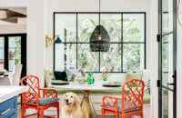 A happy dog in a beautiful kitchen remodel standing by the breakfast nook seating area with a built-in banquette table just off the kitchen and near the blue-painted kitchen island.