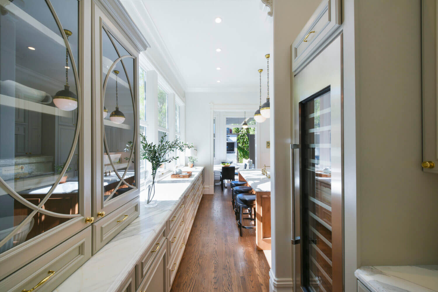 A galley kitchen design with elegant glass cabinet doors with a light gray painted finish.