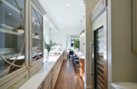 A galley kitchen design with elegant glass cabinet doors with a light gray painted finish.