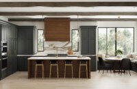 Dark gray-green and rich stained wood kitchen with modern farmhouse style, shiplap wood hood, shiplap kitchen island end cap, and brassy hardware and fixtures. Features floor-to-ceiling dark gray painted cabinets.