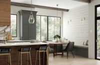 Dark gray-green and rich stained wood kitchen with a breakfast nook and built-in seating in a new modern farmhouse. A shiplap accent wall adds a farmhouse style to the dining area.