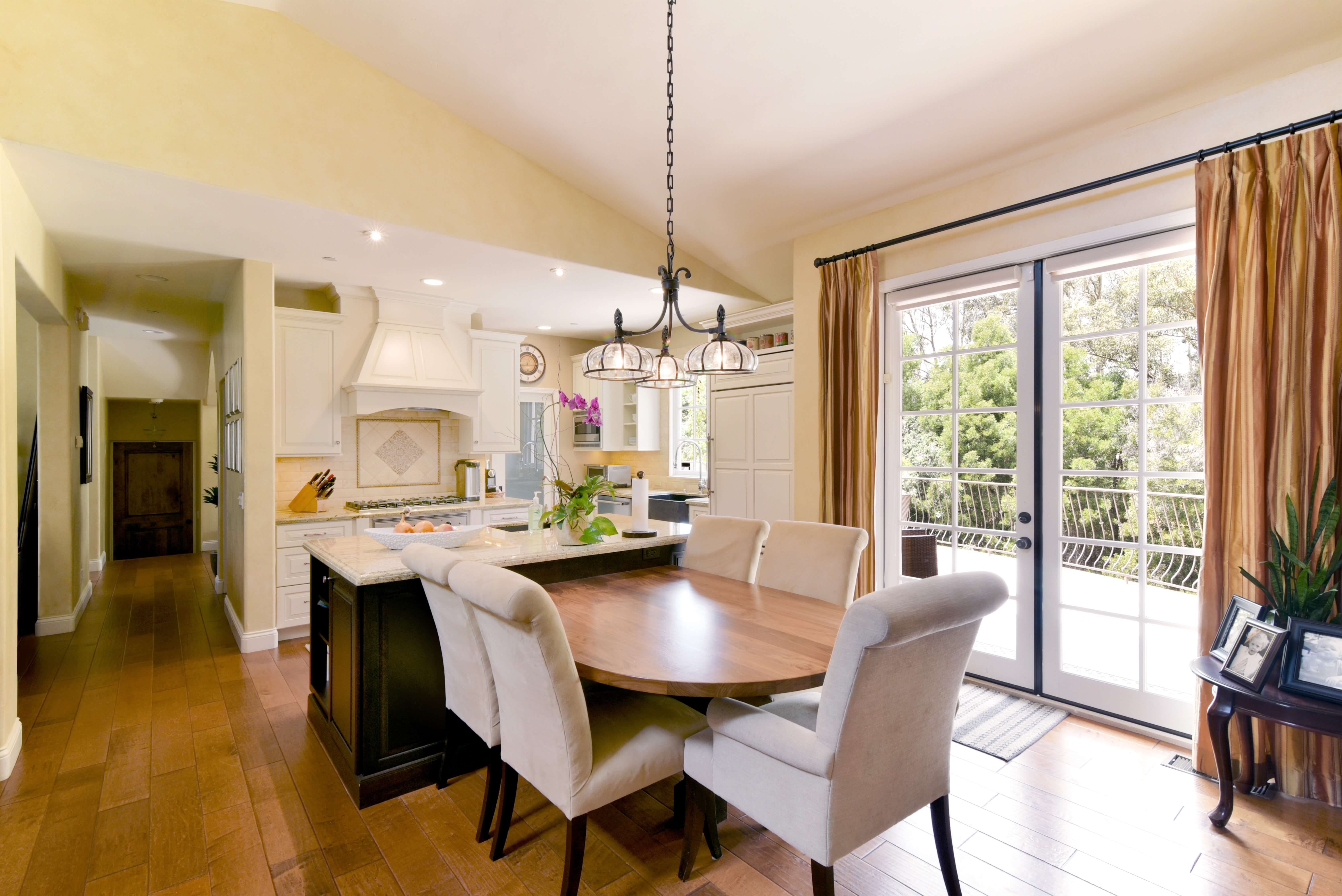 A country kitchen with a kitchen island that is combined with a traditional styled dining room table.