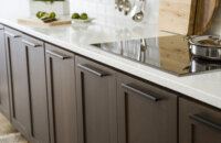 Cherry kitchen cabinets with a dark brown stain color with bright white countertops in a modern industrial style kitchen remodel.