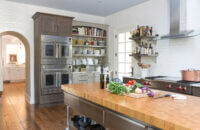 A long island with a butcher block countertop provides a large work service for food prep.