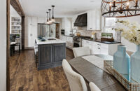 A view from the dining room into the kitchen with white and gray stained cabinets.