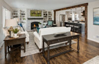 A beautiful living room next to the kitchen with a built-in entertainment center around the fireplace with white painted bookcases and cabinets and a dark gray stained fireplace mantel shelf.