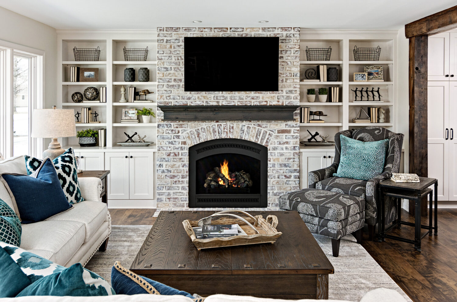A fireplace entertainment center wall with a TV mounted about the fireplace surrounded by built-in bookcases and a gray stained mantel shelf.