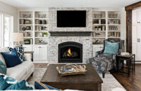 A fireplace entertainment center wall with a TV mounted about the fireplace surrounded by built-in bookcases and a gray stained mantel shelf.