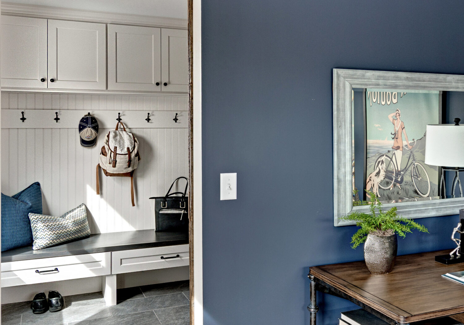 A view into the mudroom entry from the home office with a boot bench and locker cabinets with hooks.