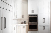 This corner of the kitchen has counter space set into the corner next to a wall of cabinetry that houses the double wall ovens as well ask storage for baking supplies and pantry goods.