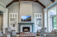 This family room features a green painted fireplace mantel with white painted cabinets flanking the fireplace and built into the walls.