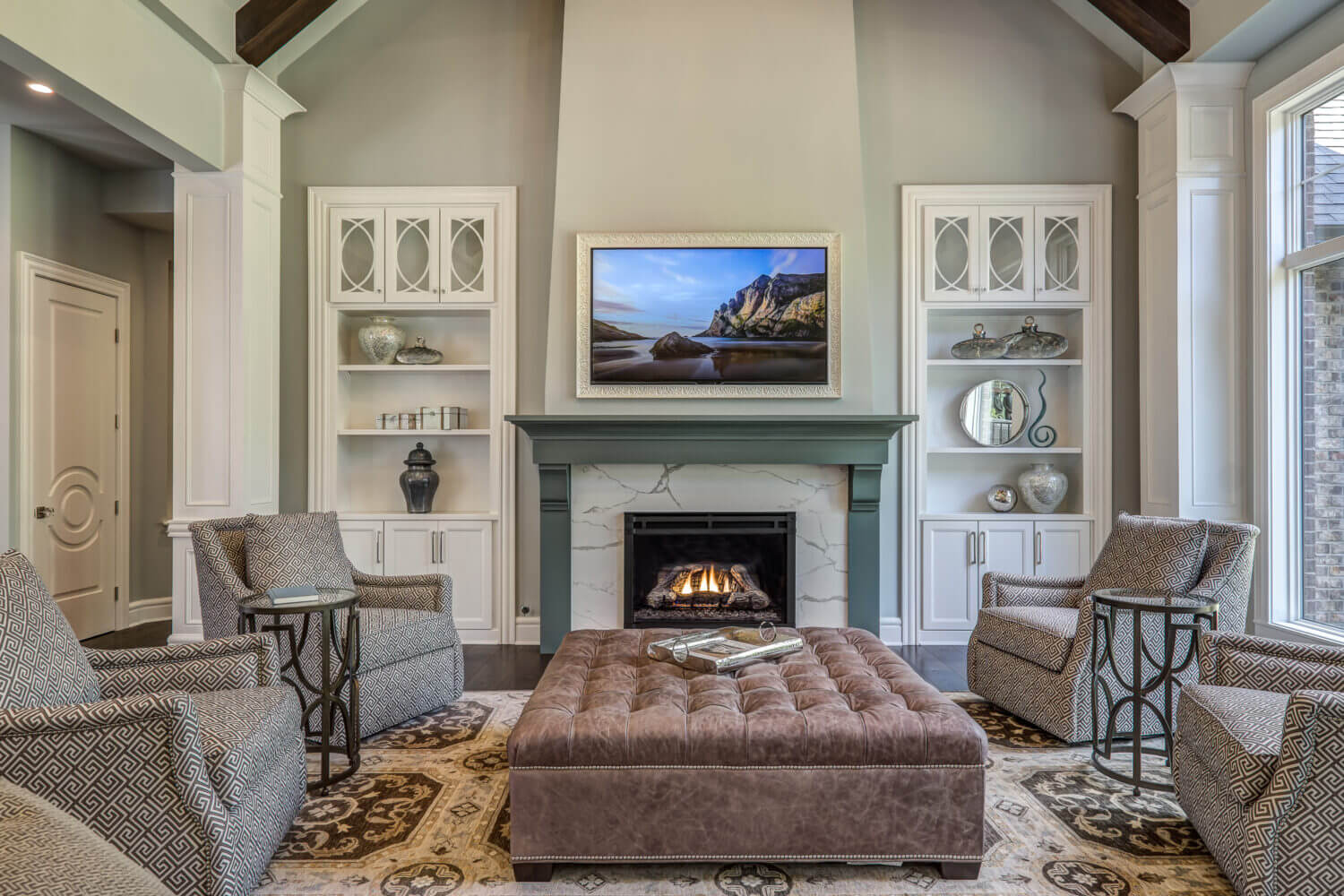 The cabinets flanking the fireplace have a white paint and delicate glass doors. The painted fireplace mantel has a dark green paint color.