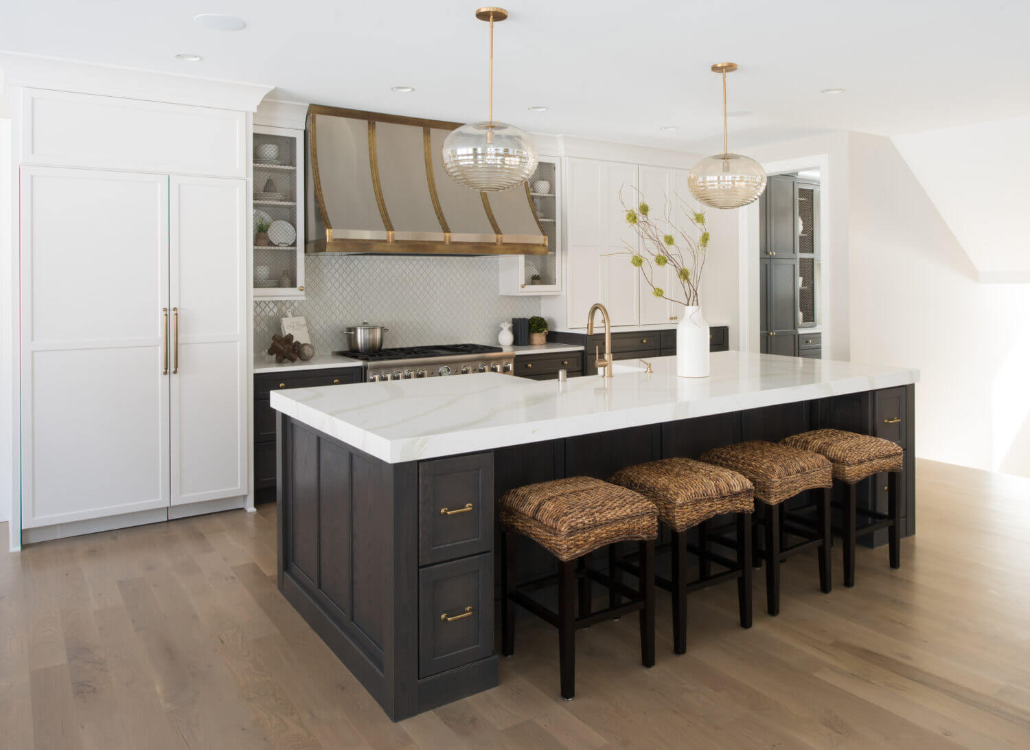 The cabinetry in this kitchen showcases Dura Supreme’s Kendall Panel flat panel door style in “Linen White” paint on the perimeter and the “Smoke” stained finish on Oak for the kitchen island, butler’s pantry, and lower base cabinets.