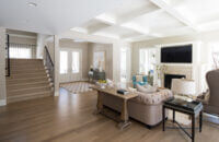 A look over the couch in the living room showing the fireplace mantel that coordinates with the kitchen cabinets and millwork throughout the home.