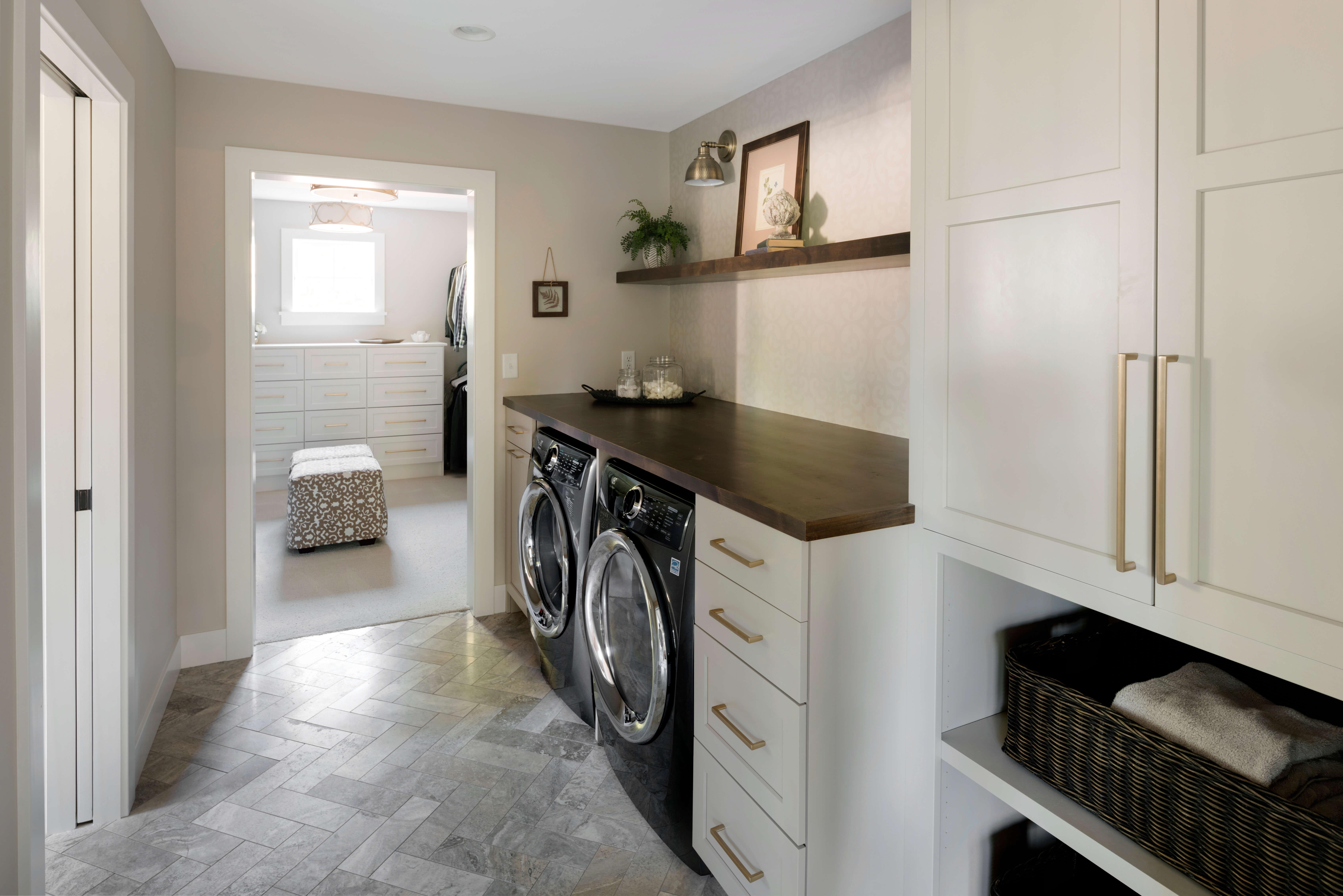 This laundry room is part of the master bedroom's grand walk-in closet. The off-white painted cabinets feature a classic shaker door style.