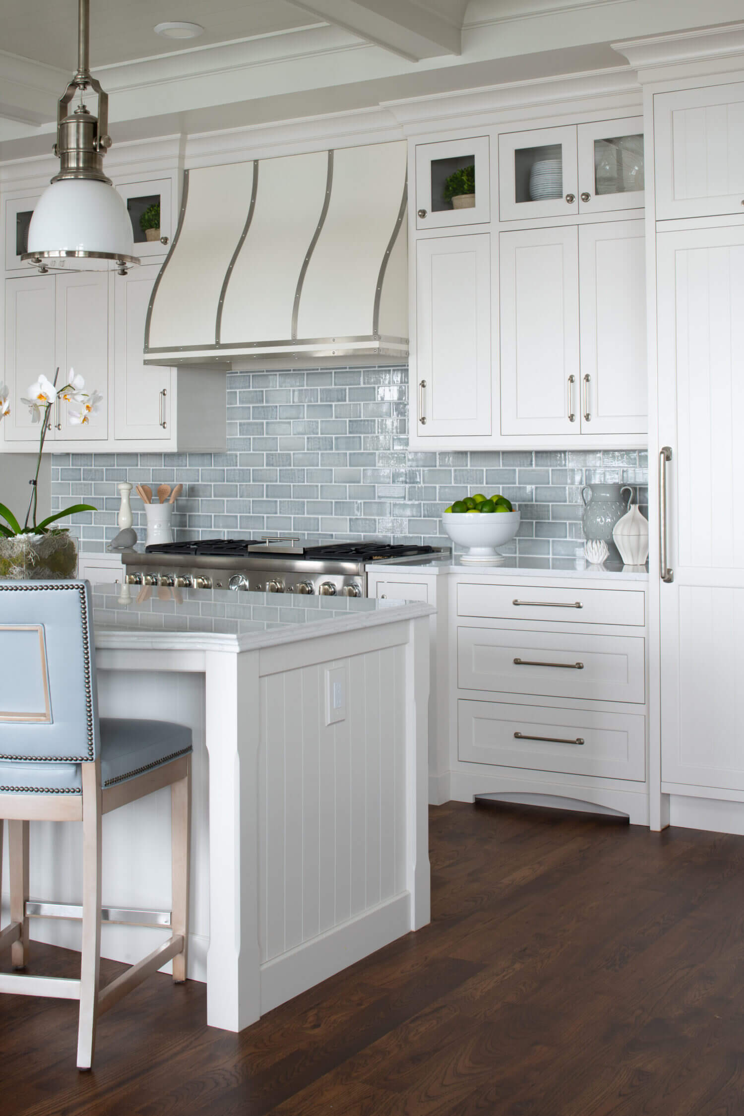 An East coast shingle styled kitchen with a symmetrical design using white painted inset cabinets and shiplap details at the end of the kitchen island.