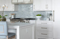 An East coast shingle styled kitchen with a symmetrical design using white painted inset cabinets and shiplap details at the end of the kitchen island.