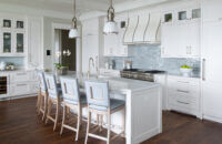 An East coast shingle styled kitchen with a symmetrical design using white painted inset cabinets and shiplap details.