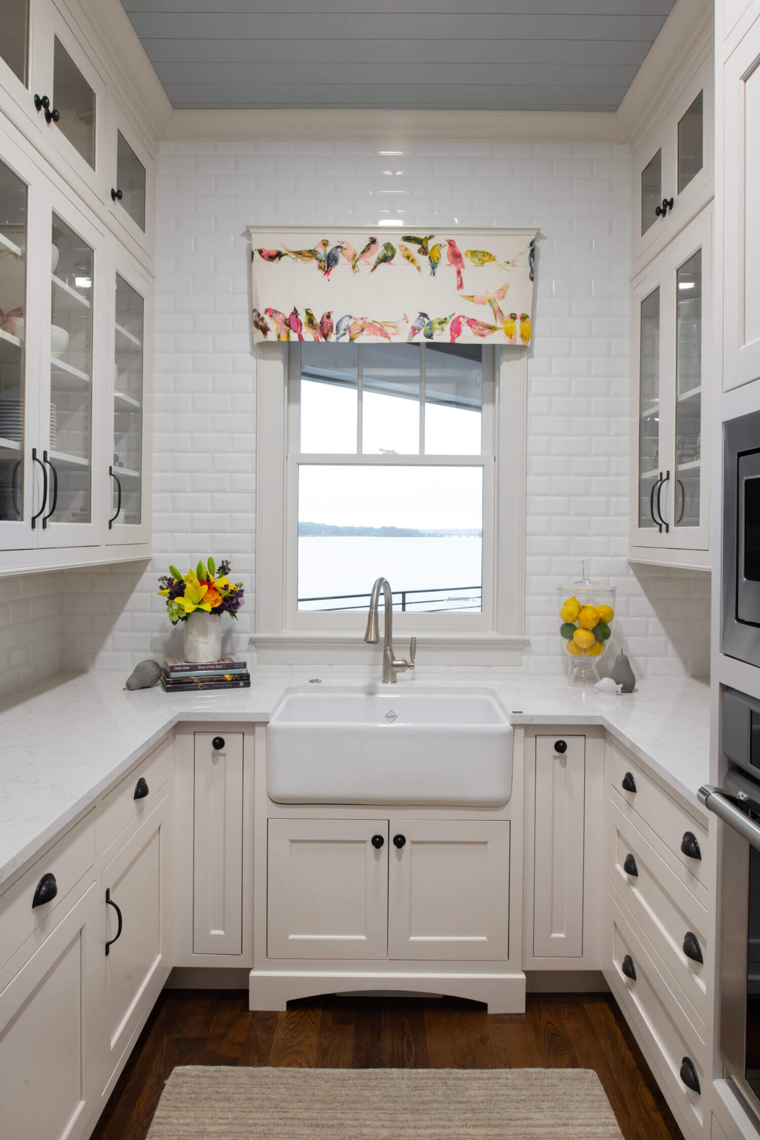 An adorable butler's pantry with white painted inset cabinets, an apron farmhouse sink and glass cabinet doors.