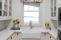 An adorable butler's pantry with white painted inset cabinets, an apron farmhouse sink and glass cabinet doors.