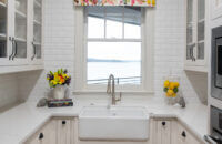 An adorable butler's pantry with white painted inset cabinets, an apron farmhouse sink and glass cabinet doors.