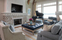 A coastal style living room with built-in bookcases and cabinetry from Dura Supreme with a beautiful fireplace design.
