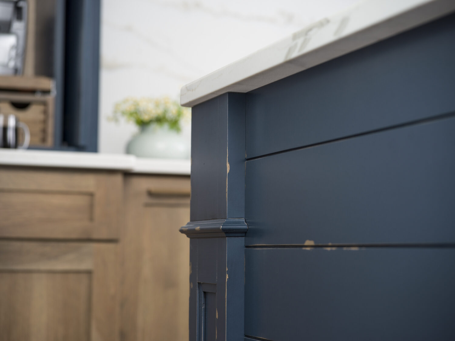 A close up of the kitchen island end cap with shiplap panels and a decorative column with a distressed navy blue painted finish.