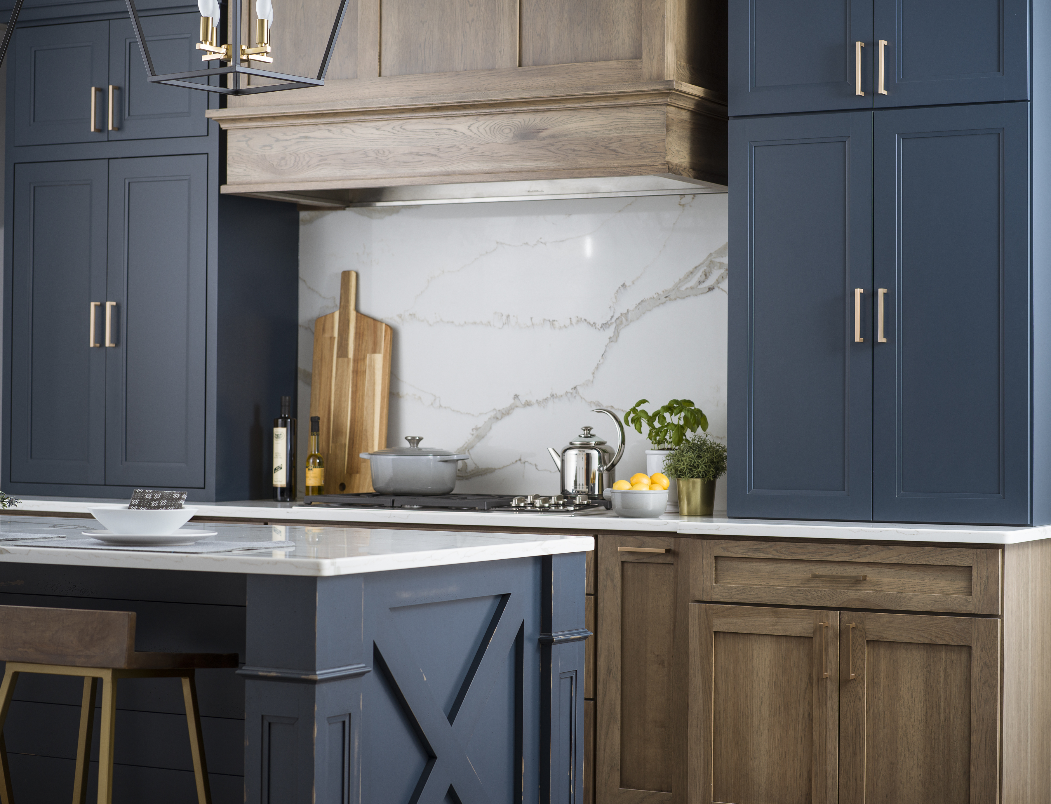 An elegant modern farmhouse remodeled with navy blue and hickory wood cabinets with a hickory wood hood and a kitchen island with an X-shaped end cap and shiplap details.