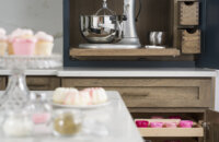 A customized baking station in the kitchen with a large mixer on a flat roll-out shelf and a cabinet below with several roll-out selves in multiple sizes.