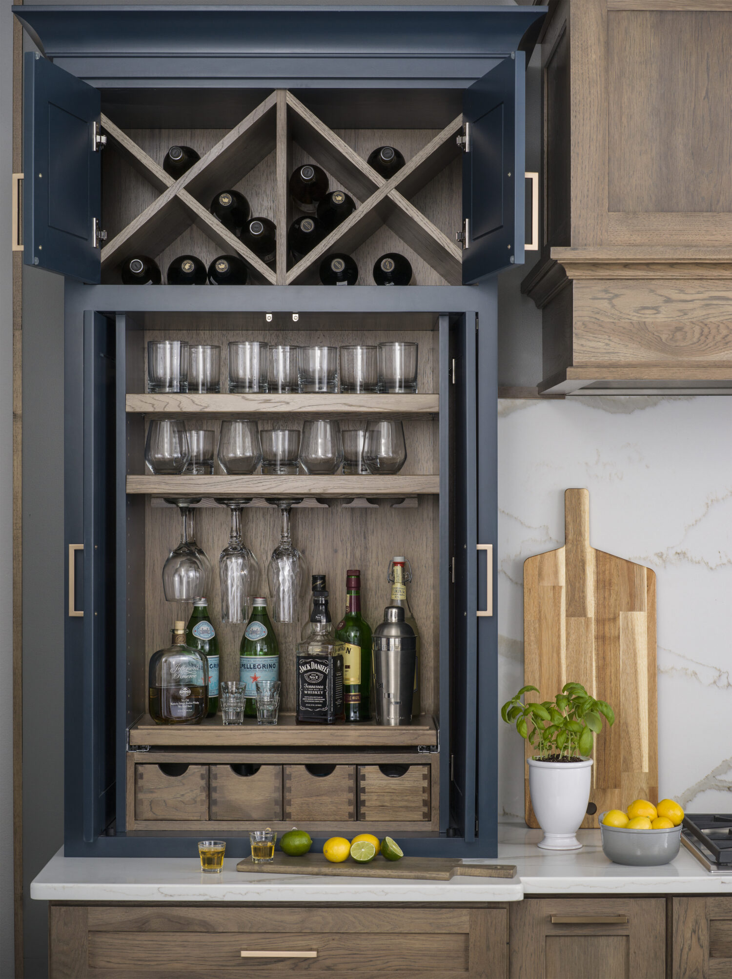 A home bar larder cabinet with a wine glass rack,, appothacary drawers, a roll-out shelf, glassware storage and wine racks above.