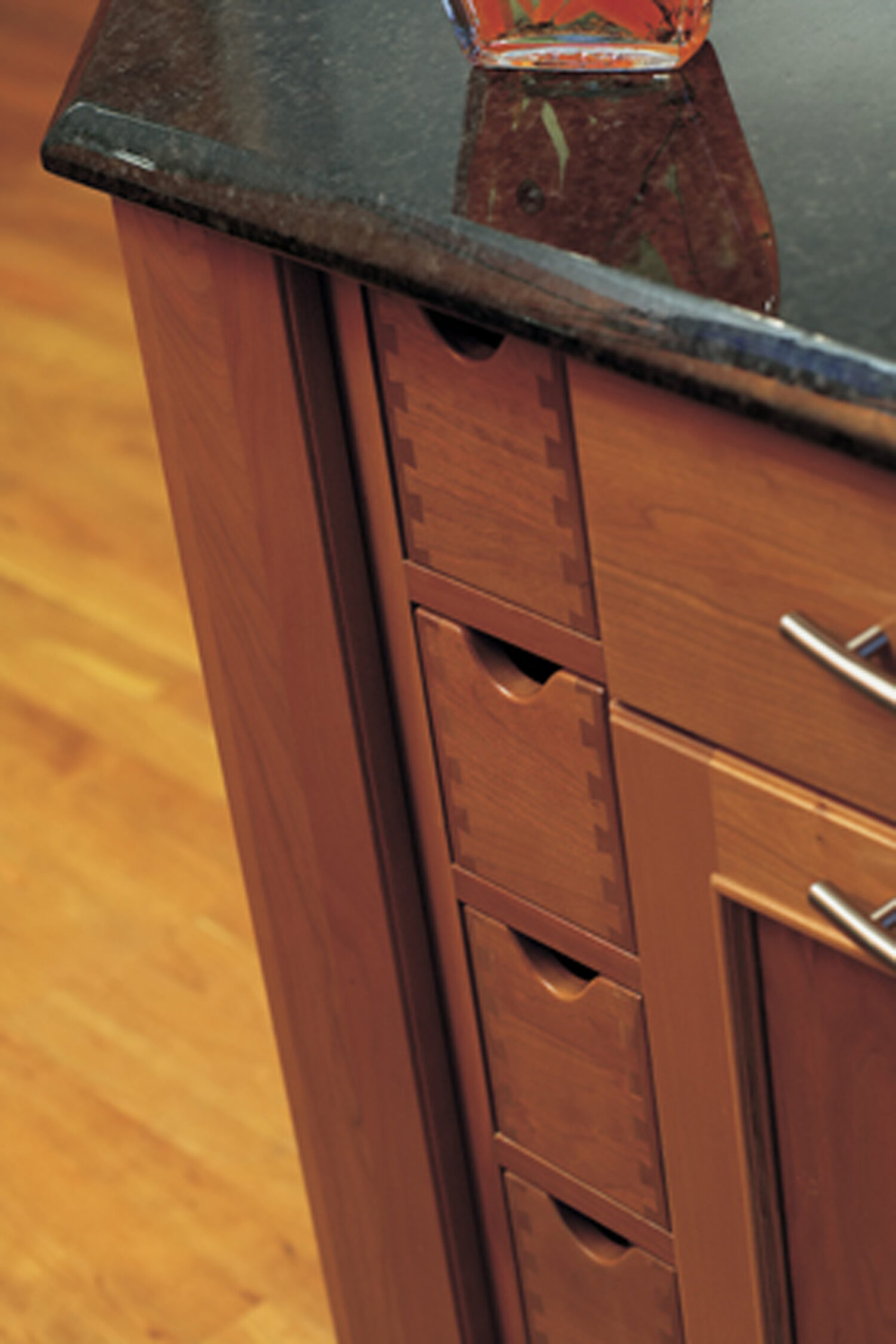 Vertical apothecary drawers in a cherry wood kitchen island with a rich-warm stain color. Kitchen island cabinets and storage from Dura Supreme.