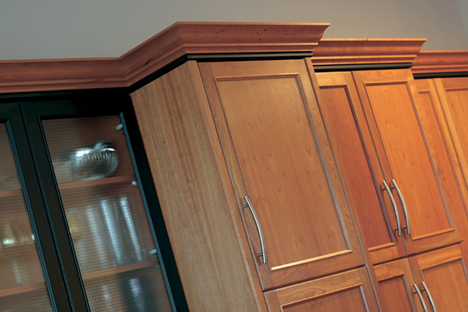 Two toned crown molding at the top of kitchen cabinets in a cherry wood kitchen with a transitional style.