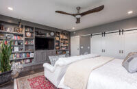 A built-in entertainment center with gray painted cabinets in a master bedroom.