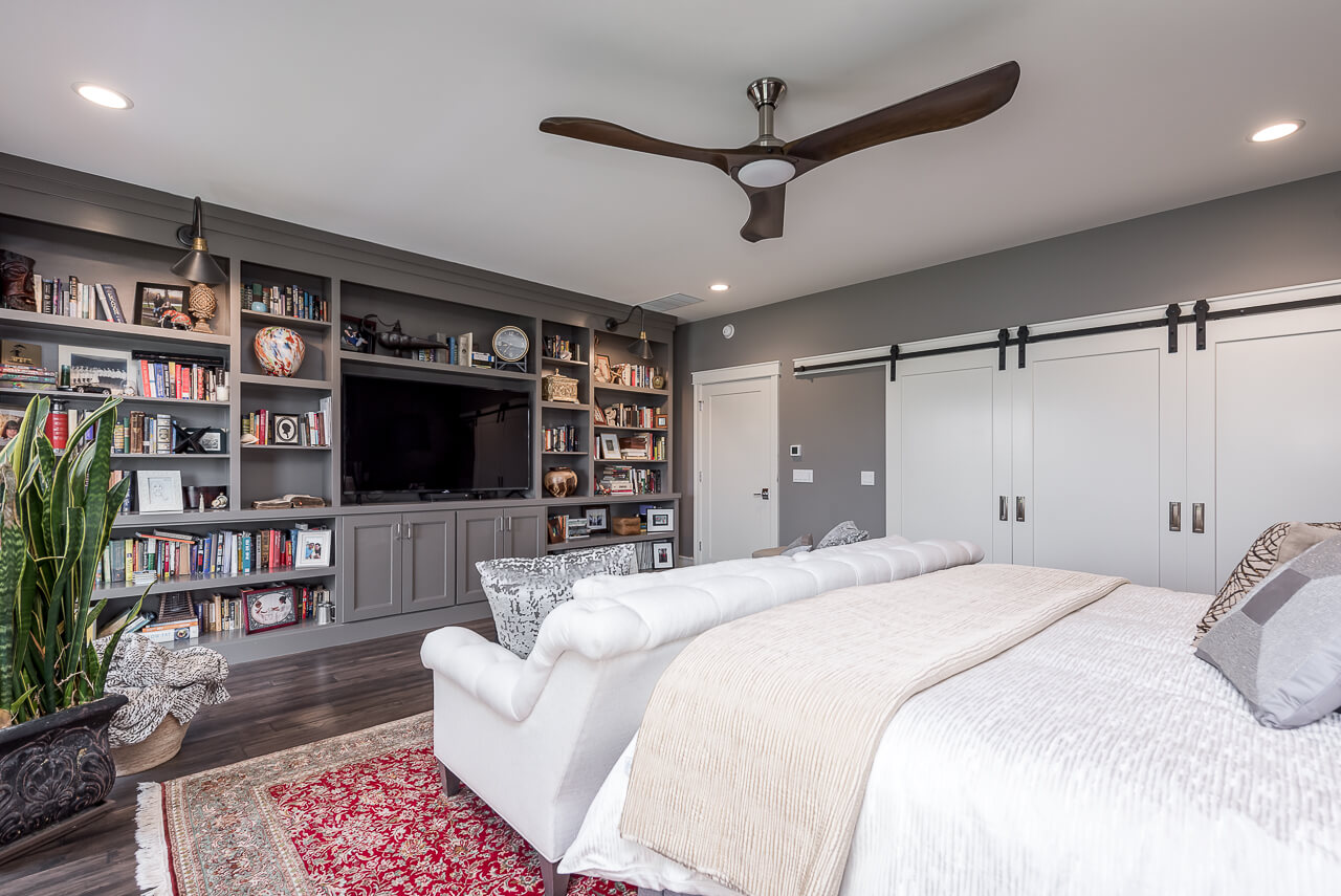 A built-in entertainment center with gray painted cabinets in a master bedroom.