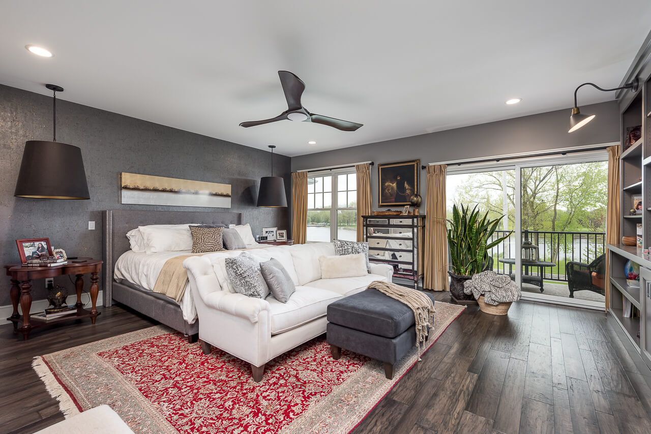 A gray master bedroom with a dark stained wood floor.