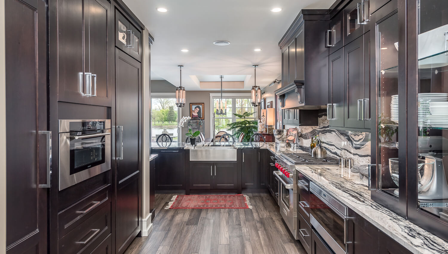 A dark kitchen with black stained cherry cabinets from Dura Supreme Cabinetry and beautiful black and white granite countertops.