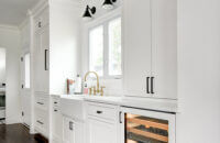 The wall with the sink in this kitchen has a beautiful window view, lots of counter space on both sides of the sink, tons of cabinet storage, and a below counter beverage fridge at the end nearest the dining space.