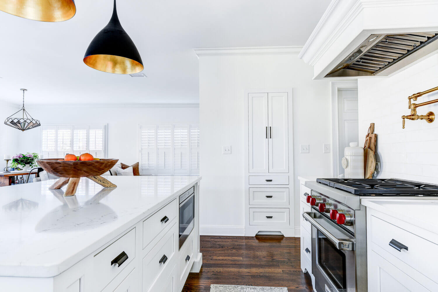A linen cabinet is recessed into the wall for additional hallway storage that coordinates with the bright white kitchen cabinetry.