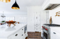 A linen cabinet is recessed into the wall for additional hallway storage that coordinates with the bright white kitchen cabinetry.