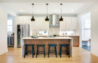 A cutting-edge modern kitchen remodeled with frameless full overlay cabinets from Dura Supreme with a waterfall kitchen island and two toned cabinetry.