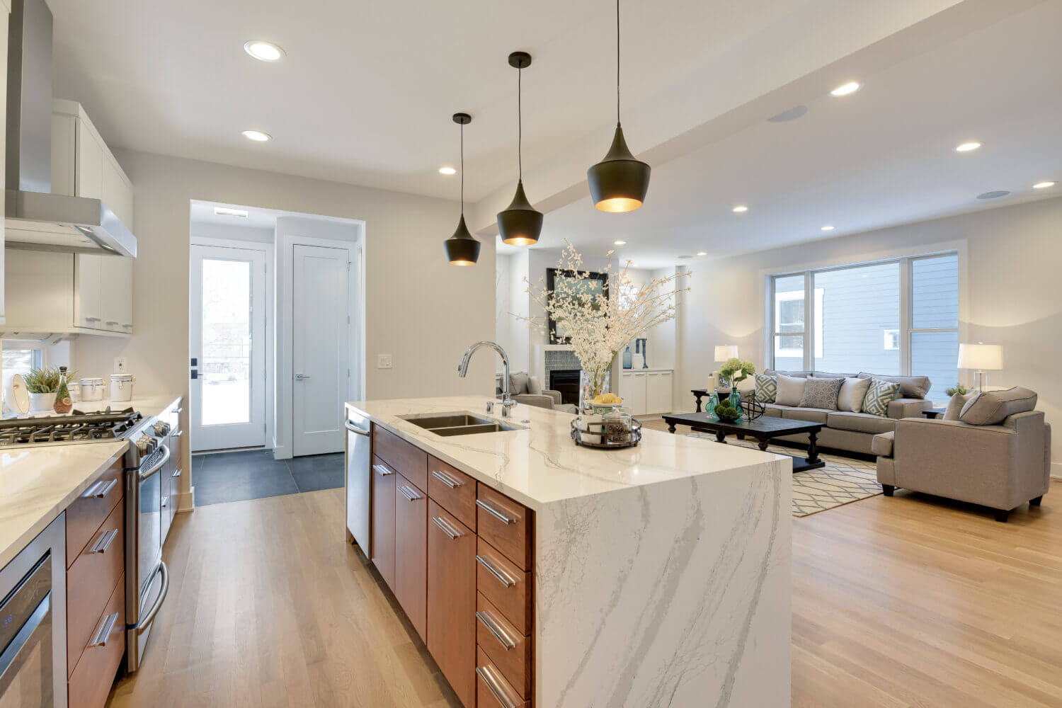 An angled view of the waterfall kitchen island with sleek slab cabinet doors and a warm wood color.