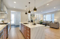 An angled view of the waterfall kitchen island with sleek slab cabinet doors and a warm wood color.